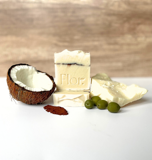 Cocoa unscented natural handmade soap bar is displayed with its ingredients coconut, cocoa powder, olives and cocoa butter. Its has a textured top and its decorated with a cocoa powder line going through the bar of soap.  Vegan soap.  Handmade soap UK. Handmade soap company based in Scotland, UK. 