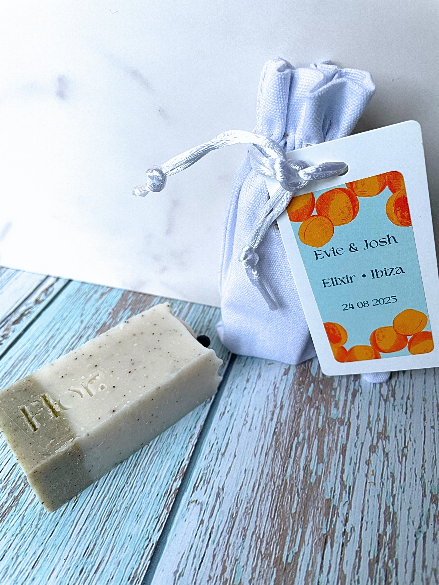 Natural min soap bar used as wedding or event favour scented with eucalyptus and rosemary and enriched with ground apricot stones to exfoliate the skin.  Encased in a luxury white cotton bag with silk draw strings. Includes an information tag using colourful branding of apricot illustrations colours of orange and blue.  Can be used for weddings, baby showers, corporate events and corporate gifting.  