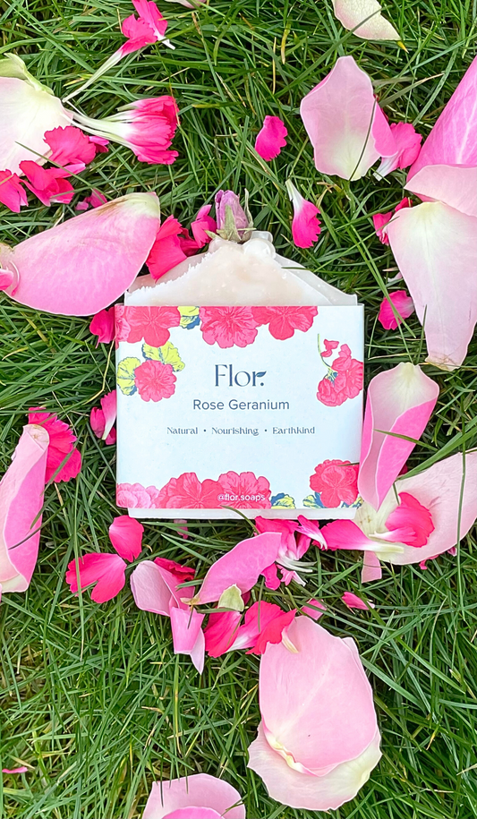 Rose Geranium vegan soap and natural handmade soap bar for vegan and natural skincare has a dried rose bud on the to of it.  It has soft pink swirls made my French pink clay.  It has colourful packaging with a green background and pink rose geranium illustrations. Handmade soap UK. Handmade soap company.