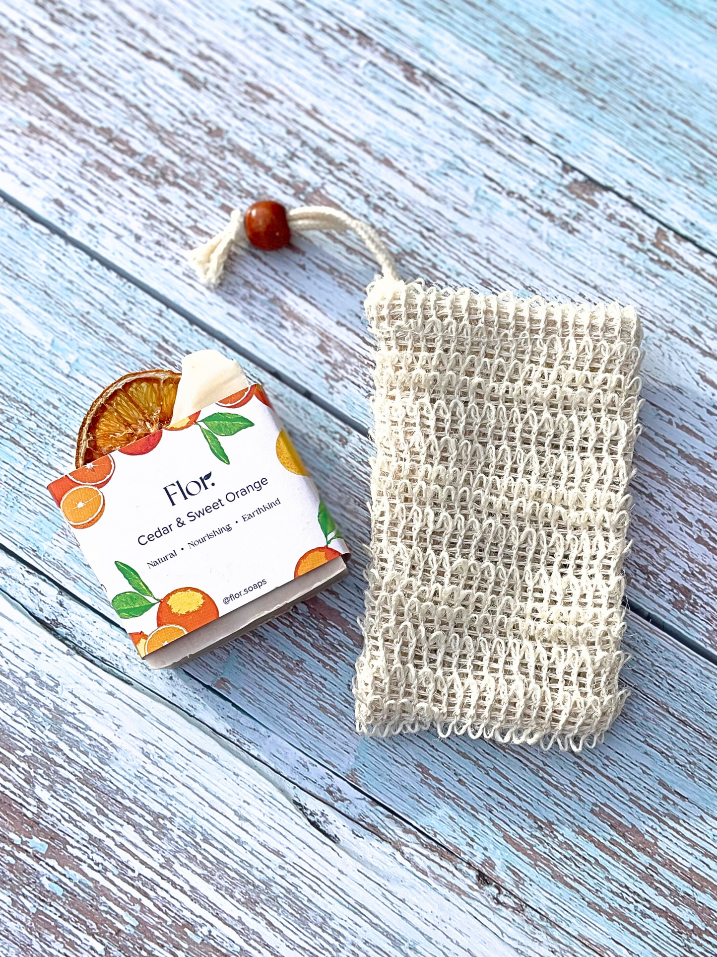 A sisal soap pouch is a eco-friendly option for storing your natural soap bar.  This beige pouch can hang in your shower for you to use with your soap bar inside. It is a natural skin exfoliant and can improve blood circulation. Shown here with our cedar and sweet orange soap bar that has its botanic packaging on including illustrations of oranges. 